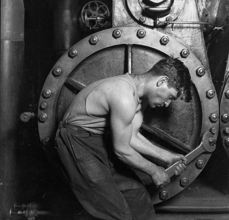 Hart arbeitender Mechaniker, der eine Maschine in Stand setzt.