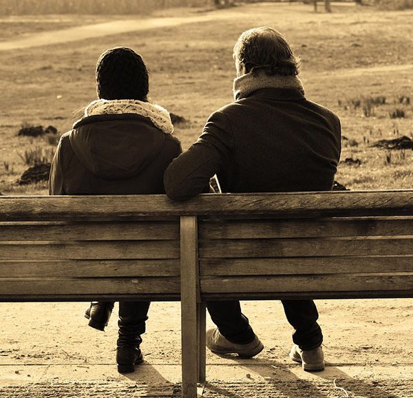 Zwei Menschen sitzen auf einer Bank und reden